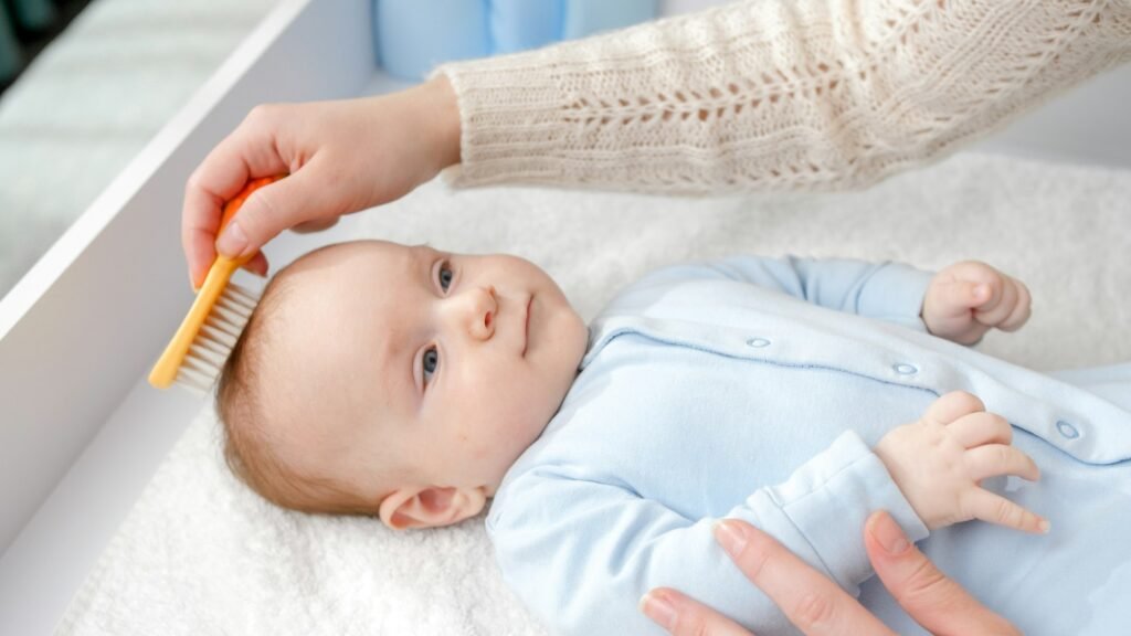 CLoseup of young mother combing her baby son hair with hair brush. Concept of hygiene, baby care and